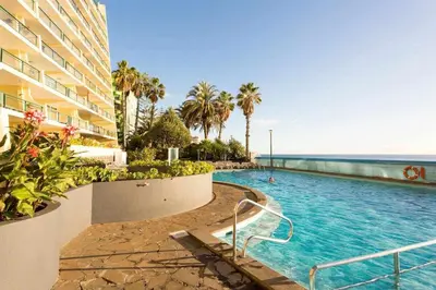 a swimming pool next to a building and the ocean at Formosa Sunset - Em frente à praia com wifi in Panasqueira