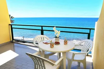 a table and chairs on a balcony with the ocean at Formosa Sunset - Em frente à praia com wifi in Panasqueira