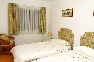 a bedroom with two beds and a chair at Formosa Sunset - Em frente à praia com wifi in Panasqueira