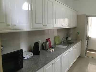 a kitchen with white cabinets and a black microwave at Rocha Mar 3M in Ribeira Brava