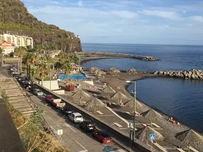 a busy street with cars parked next to the ocean at Rocha Mar 3M in Ribeira Brava