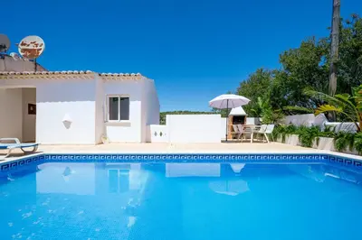 a swimming pool with a house and an umbrella at Monte Sao Pedro - Villa in Luz