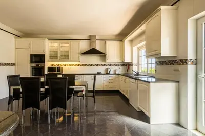 a kitchen with white cabinets and a table and chairs at Casa Clementina in Lagos