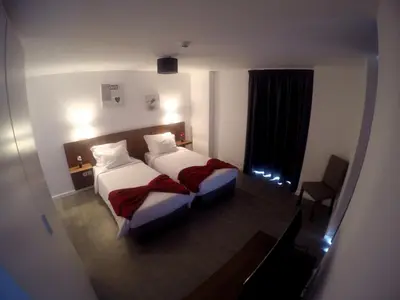 a hotel room with two beds and a window at Albergaria O Professor in Santa Cruz