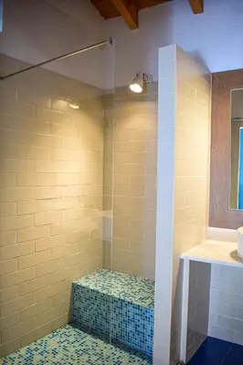 a bathroom with a shower with a bench in it at Casinhas da Figueira in Budens