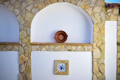 a stone wall with two arches and a vase at Casinhas da Figueira in Budens