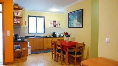 a kitchen with a red table and chairs in a room at Apartamento Barros in Estreito de Câmara de Lobos