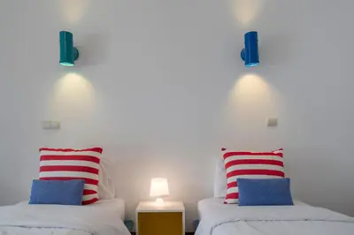 two beds with red white and blue pillows in a room at Piscina fantástica no centro da cidade! in Funchal