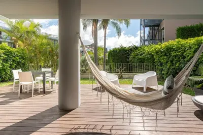 a hammock on a patio with chairs and a table at Piscina fantástica no centro da cidade! in Funchal