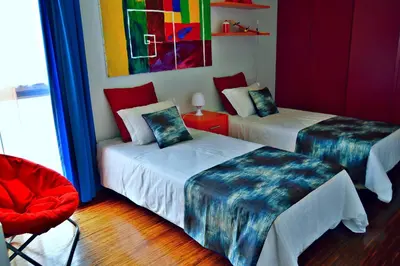 a room with two beds and a red chair at vista dos arrifes in Funchal