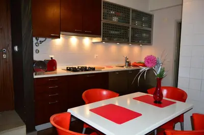 a kitchen with red chairs and a table with a vase of flowers at vista dos arrifes in Funchal