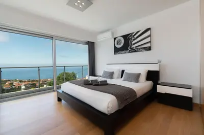 a bedroom with a large bed and large windows at Villa Panoramica II in Arco da Calheta
