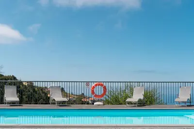 a swimming pool with lounge chairs and a volley ball hoop at Villa Panoramica II in Arco da Calheta