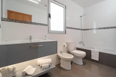 a white bathroom with a toilet and a sink at Villa Panoramica II in Arco da Calheta