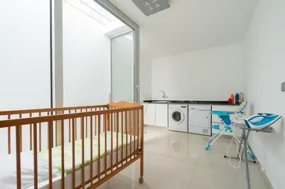 a room with a crib and a washing machine at Villa Panoramica II in Arco da Calheta