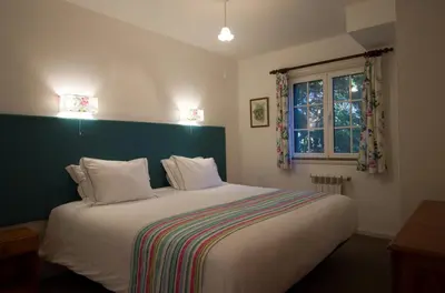 a bedroom with a large white bed with a green headboard at Quinta Santo Antonio Da Serra in Santa Cruz