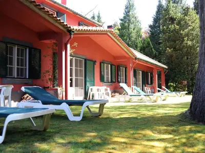an orange house with chairs in the yard at Quinta Santo Antonio Da Serra in Santa Cruz
