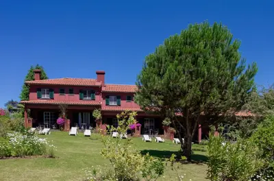 a large red house with chairs and a tree at Quinta Santo Antonio Da Serra in Santa Cruz