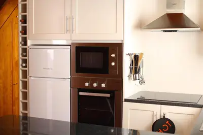 a kitchen with white cabinets and a black oven at Casa da Rainha Bungallow in Estreito da Calheta