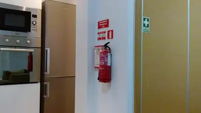 a refrigerator with a fire extinguisher on a wall at Sweet Home for Holidays in Machico