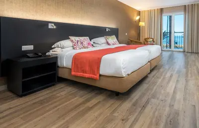 a bedroom with a large bed with a red blanket at Enotel Sunset Bay in Ponta do Sol