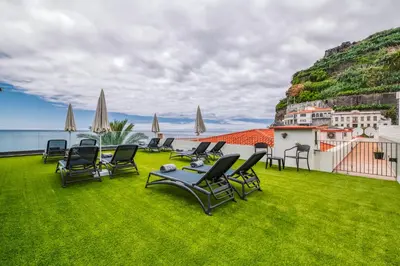 a group of chairs and tables on a lawn at Enotel Sunset Bay in Ponta do Sol