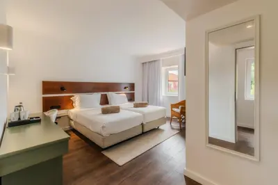 a bedroom with a bed and a desk and a mirror at Enotel Santo da Serra in Santo da Serra