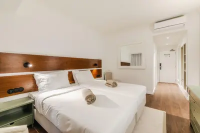 a bedroom with two beds with white sheets and a wooden headboard at Enotel Santo da Serra in Santo da Serra