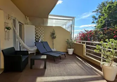 a patio with two chairs and a hammock on a balcony at Refugio Madeira in Caniço