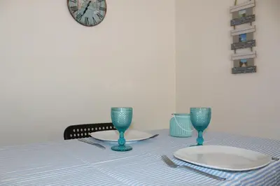 a table with a plate and two glasses and a clock at Refugio Madeira in Caniço