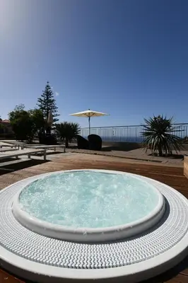 a large pool of water on a deck with an umbrella at Hotel Do Campo in Ribeira Brava
