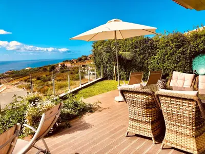 a patio with a table and chairs and an umbrella at Villa Pinheira II in Estreito da Calheta