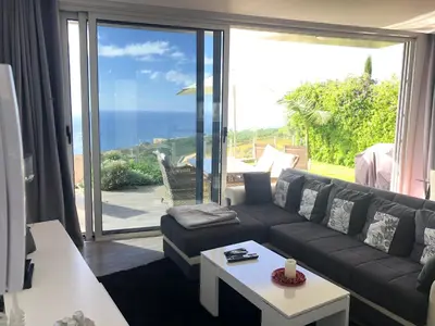 a living room with a couch and a view of the ocean at Villa Pinheira II in Estreito da Calheta