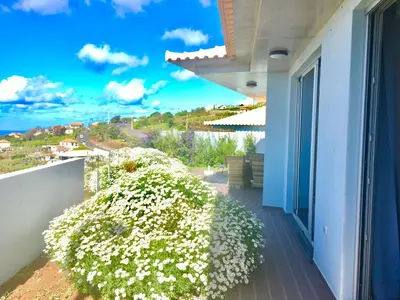 a balcony with white flowers on a house at Villa Pinheira II in Estreito da Calheta