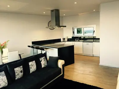 a living room with a black couch and a kitchen at Villa Pinheira II in Estreito da Calheta