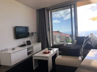a living room with a couch and a large window at Villa Pinheira II in Estreito da Calheta