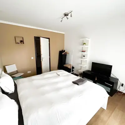 a bedroom with a large white bed and a television at Cozy Rooms Vila do bispo in Vila do Bispo