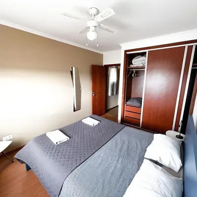 a bedroom with a bed and a ceiling fan at Cozy Rooms Vila do bispo in Vila do Bispo