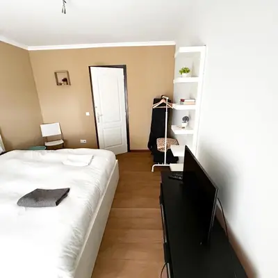 a bedroom with a bed and a flat screen tv at Cozy Rooms Vila do bispo in Vila do Bispo