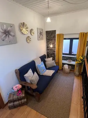 a living room with a blue couch and a window at Casa dos Avos in Calheta