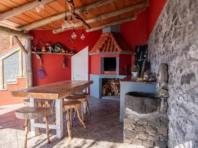 a kitchen with a wooden table and a fireplace at Casa dos Avos in Calheta