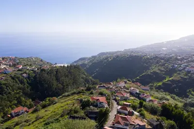 an aerial view of a village on a hill with the ocean at Casa dos Avos in Calheta
