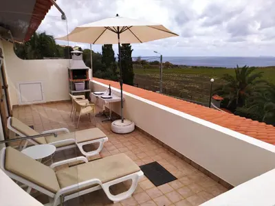 a balcony with a table and chairs and an umbrella at Beachfront House Atalaia in Caniço