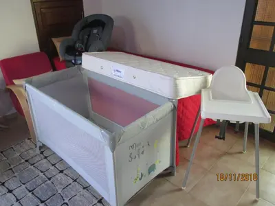 a baby crib with a table and a chair at Beachfront House Atalaia in Caniço