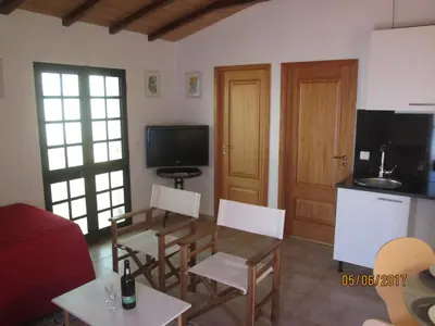 a living room with a table and chairs and a kitchen at Beachfront House Atalaia in Caniço
