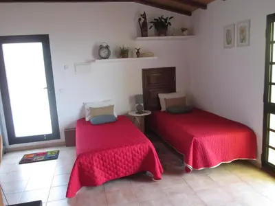 two beds in a room with red sheets at Beachfront House Atalaia in Caniço