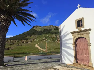 a church with a palm tree and a mountain at Paradise Beach in Porto Santo