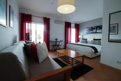 a bedroom with a bed and a couch and a table at Oasis Beach Apartments in Luz