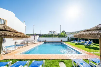 a swimming pool with chairs and umbrellas at Oasis Beach Apartments in Luz