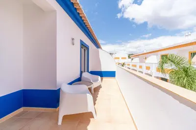 a balcony with white and blue walls and white chairs at Oasis Beach Apartments in Luz